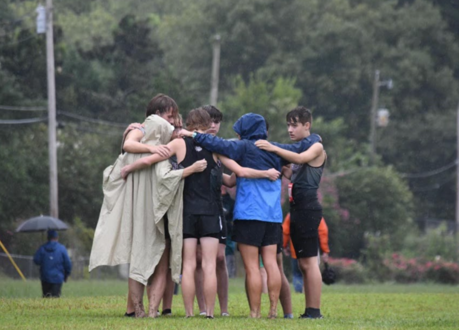 Coach Ashley Schott huddles with the boys cross country team after a recent meet.
