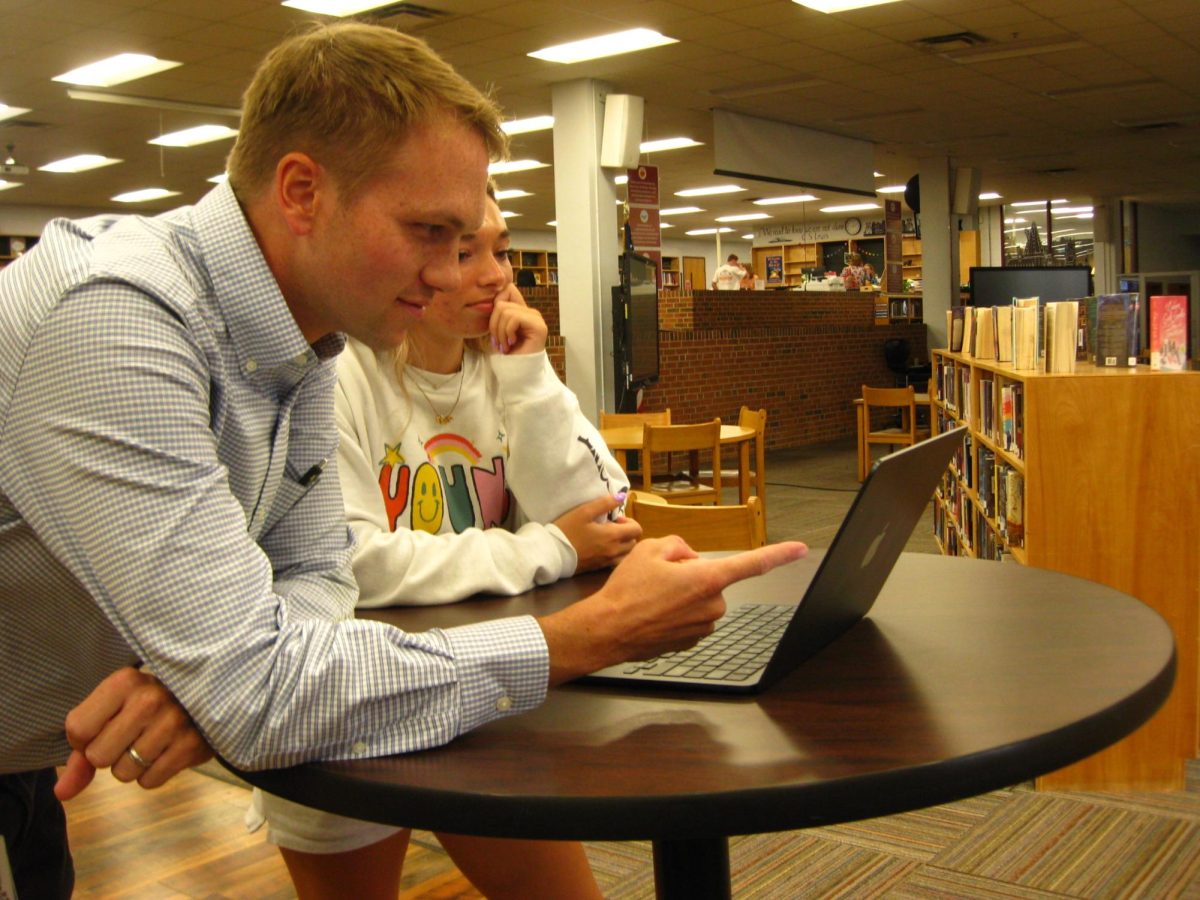 Senior Committee sponsor Mr. Logan Peterson plans for the next food trucks day with senior Stella Cross.
