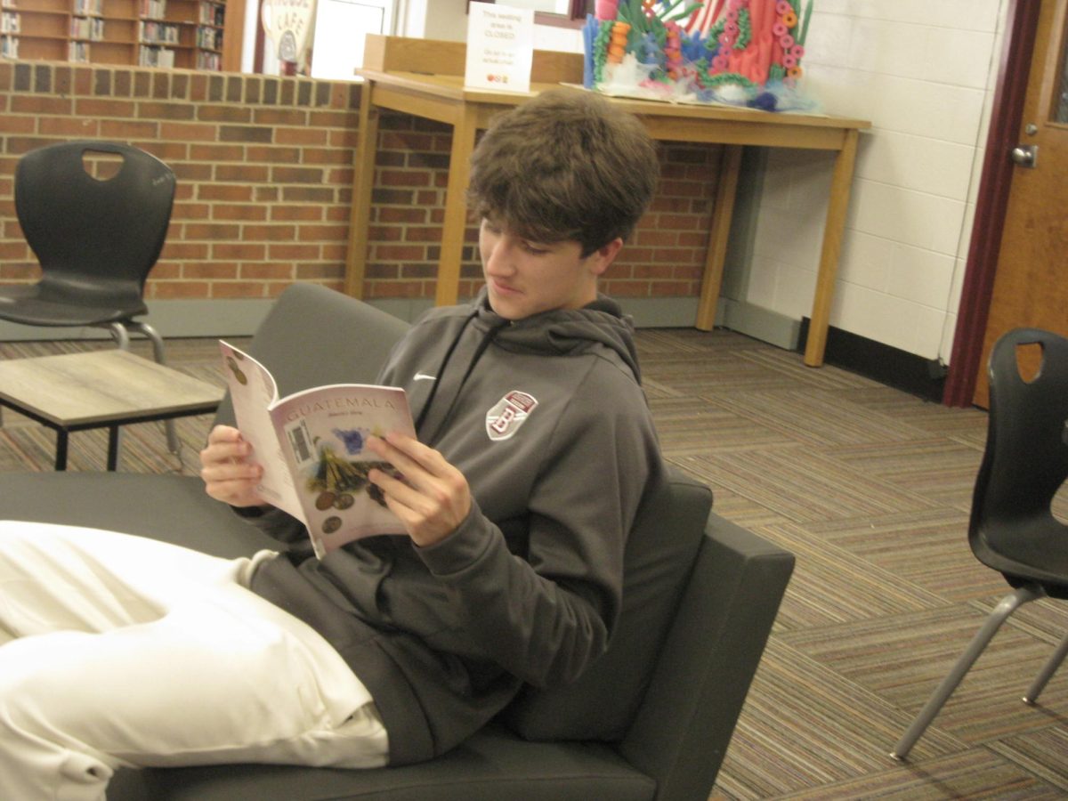 Bearden junior Ben Prins reads one of Mrs. Anna Saeli's books in the Bearden library.